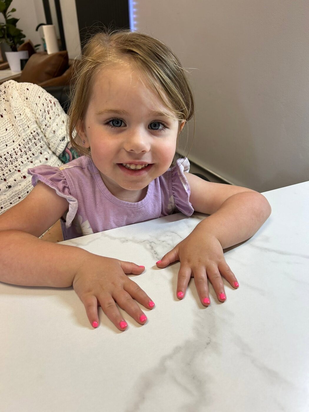 Little girl smiling with a bright pink mini manicure